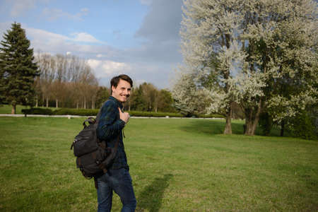 Young guy with a backpack in the park, green backgroundの写真素材