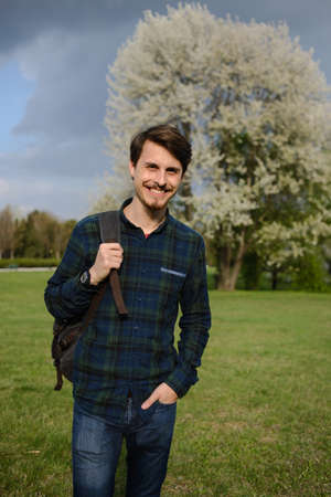 Young guy with a backpack in the park, green backgroundの写真素材