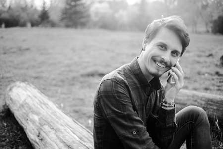 Handsome guy talking on the phone in the parkの写真素材