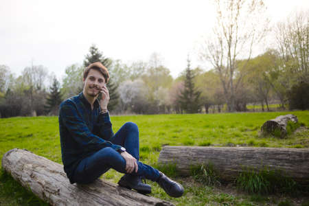 Handsome guy talking on the phone in the parkの写真素材