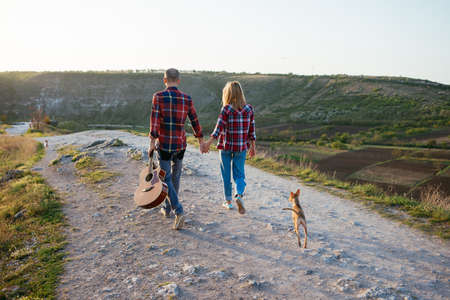 Young couple in love sitting on the park  while these young guitar playing guitar in sunset time....