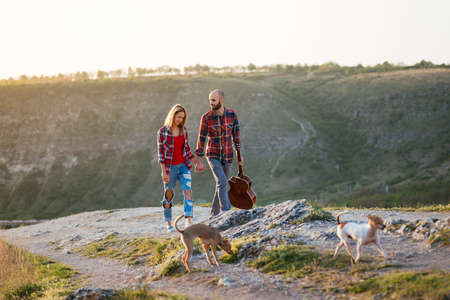 Young couple in love sitting on the park  while these young guitar playing guitar in sunset time.の写真素材
