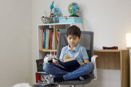 Boy reading a book while sitting on a chair