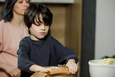 Mother and son eating noodles in the kitchen at home, focus on boyの写真素材