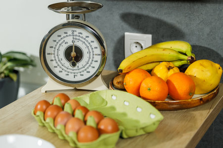 Closeup of fruits and kitchen scale on wooden table in modern kitchenの写真素材