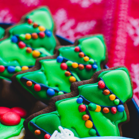Close-up of beautifully decorated gingerbread Christmas cookies made to look like lit-up Christmas trees on a platterの写真素材