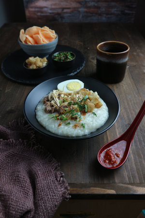Rice porridge with egg and celery in black plateの写真素材