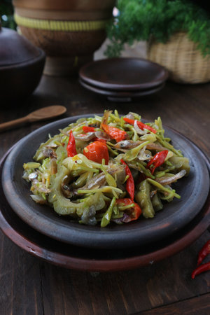 Stir-fried bitter gourd with chili and pepper on wooden backgroundの写真素材
