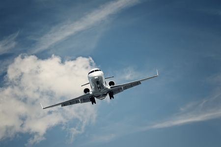 passenger private jet landing on a clear blue skyの写真素材