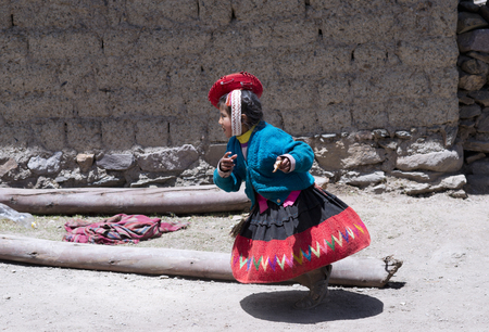 Peruvian girl running dressed in colourful traditional handmade outfit. October 21, 2012 - Patachancha, Cuzco, Peruのeditorial素材