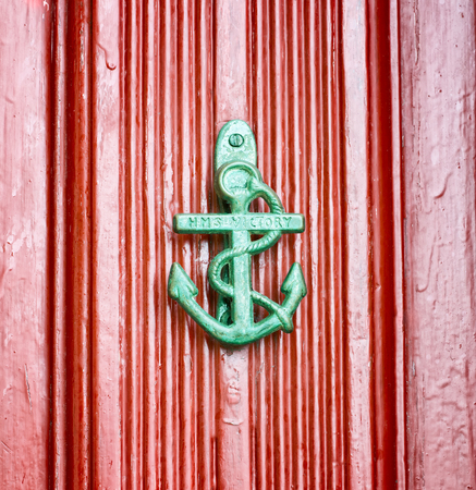 Antique anchor shaped knokcer on a red vintage doorの写真素材