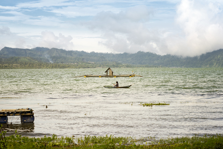 Silhouette of a boatman paddling on Lake Batur during sunset. January 11, 2014 - Bali, Indonesiaのeditorial素材