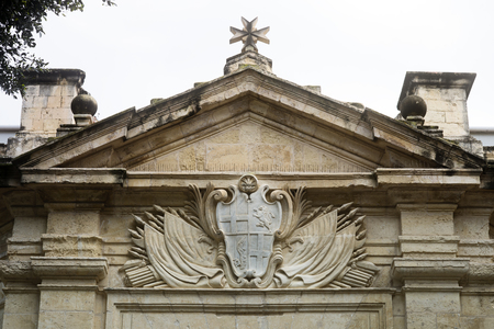 Stone Carved Coat Of Arms And Maltese Cross Above The Entrance Of The Knights Hospitallers Church, Valletta, Maltaの写真素材