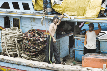 Smiling Fishermen On Wooden Boat, Two large Coiled Ropes On The Side. January 17, 2014 - Probolinggo, East java, Indonesiaのeditorial素材