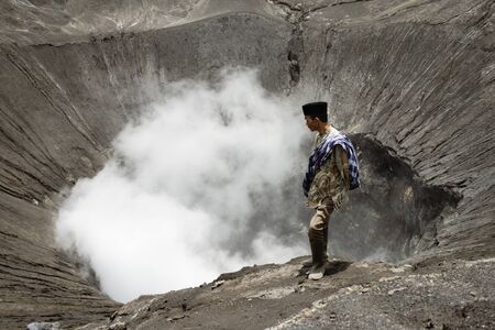 Tenggerese Man Standing On The Edge Of An Active Volcano In Bromo Tengger Semeru National Park. January 17, 2014 - Java, Indonesiaのeditorial素材
