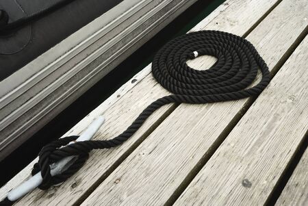 Black Swirled Mooring Rope Tied Up On A Bitt Securing Boat To Jettyの写真素材