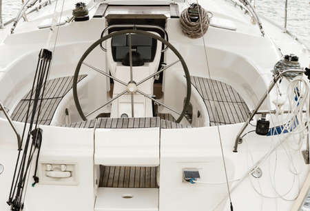 Closeup Of A Wheel And Deck Of A White Sailing Boat In Marina