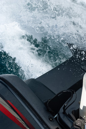 An outboard engine's lower unit and propeller at full throttle, creating a turbulent wake in the seaの写真素材