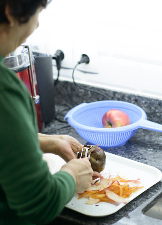 Elderly woman meticulously peels beetroot for a nutritious juice blendの写真素材