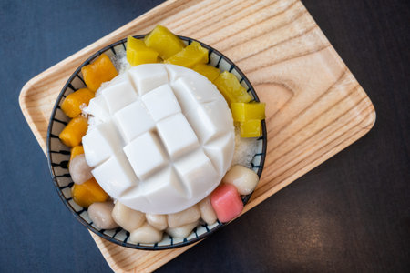 Taiwanese dessert consisting of almond jelly with sweet potato and taro balls on crushed ice in...