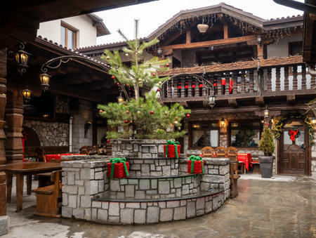 A cozy stone and wood courtyard of a traditional Bulgarian inn, decorated for the holidays with a Christmas tree and festive gift boxes.の写真素材