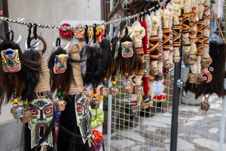 Intricately designed Kukeri masks with animalistic features and decorative wool tassels, adorned with colorful threads and small bells, hung outdoors to scare away evil spirits in Bansko, Bulgaria.の写真素材