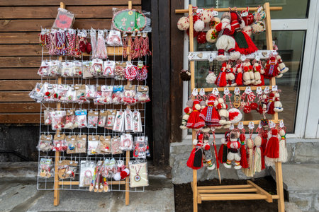 Bansko, Bulgaria - Mar 2, 2025: A vibrant outdoor display of handcrafted Martenitsa charms and traditional Bulgarian dolls, featuring red and white woven threads and woolen pompoms for Baba Marta Day.のeditorial素材