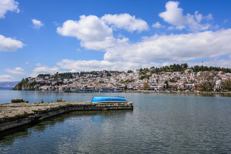 Vibrant panorama of Ohrids historic lakeside district under a bright blue sky with fluffy clouds,...