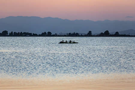 Landscape of a lagoon beach in the mediterranean sea while three people are in a kayak