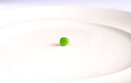 Single green pea on white plate.の写真素材