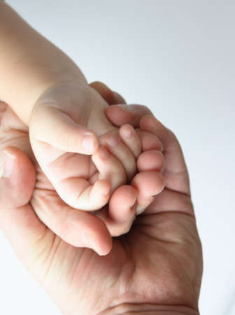 Mother, father and sun hands - three hands of different sizes holding each other - family conceptの写真素材