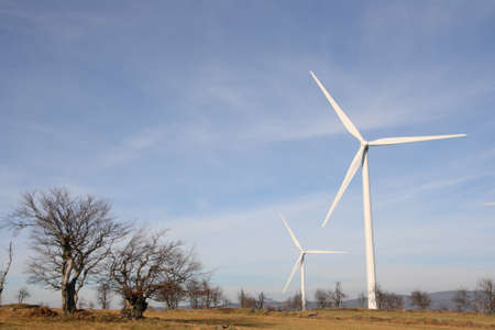 View of landscape with several windmills against blue sky generating power View of landscape with several windmills against blue sky generating power
