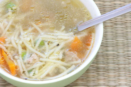 Broth soup with spoon with carrot, pea and noodlesの写真素材