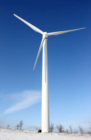 View of single windmill generating electricity against blue sky in a winter landscape