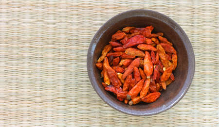 Detail view of many hot red dried chilli peppers chillies in a brown bowlの写真素材