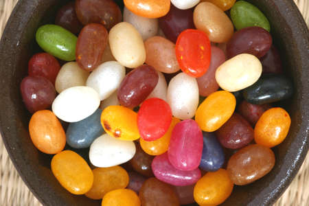 Colourful candies in a brown bowl on white backgroundの写真素材
