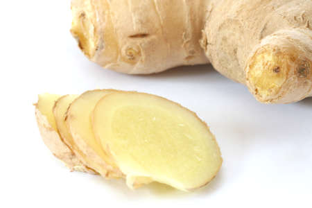 Whole raw ginger root piece with slises on white backgroundの写真素材
