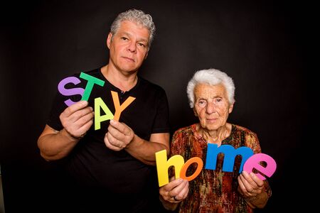 a mature man and an elderly woman holding multicolored letters that form: stay homeの写真素材