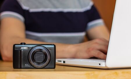 Close-up of a photo camera on the table, with a modern dressed man working at home or office. Nomadic lifeの写真素材