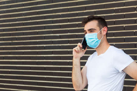 Man with disposable mask talking on phone indoors. Dangerous virus.の写真素材