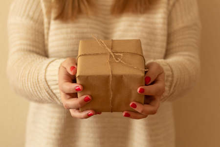 close-up of a woman's hands with red nails and with a gift. Christmas gift