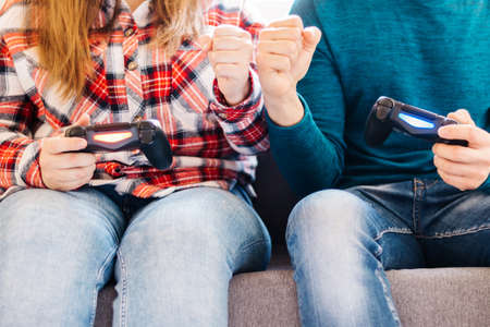 Selective focus on photo of Caucasian couple man and woman playing video games together with joysticks.Concept of player, team, love.の写真素材