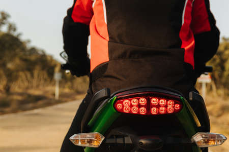 biker driving his motorcycle in a traffic jam, braking for road safety. red brake light on.