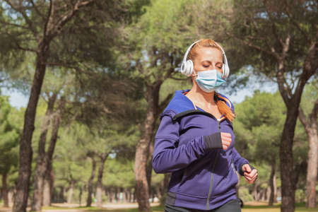 Caucasian fitness woman running and wearing a mask for protection Dust and pollution and protection...