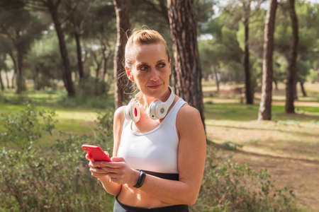 Fitness woman using her smartphone on social media while playing sports and listening to music with...