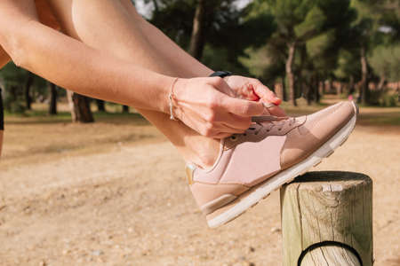 Young sportsman and female athlete tying sneakers in the park outdoors. Concept healthy lifestyle...