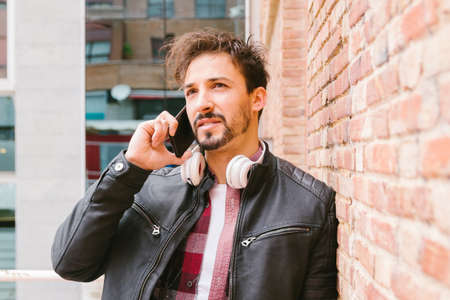 adult man walking and using a smartphone with headphones. People and lifestyles concept.