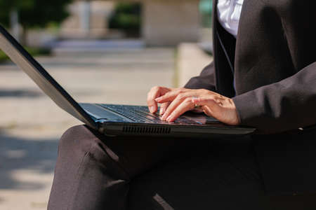 Young businesswoman with laptop sitting on stairs outside