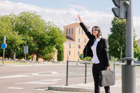 Elegant business woman stopping a taxi on the city street. Transportation conceptの写真素材