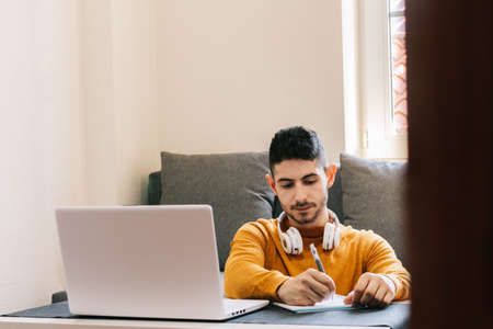 Young adult man in yellow clothes, working from home, taking stock of work and family life.Concept...